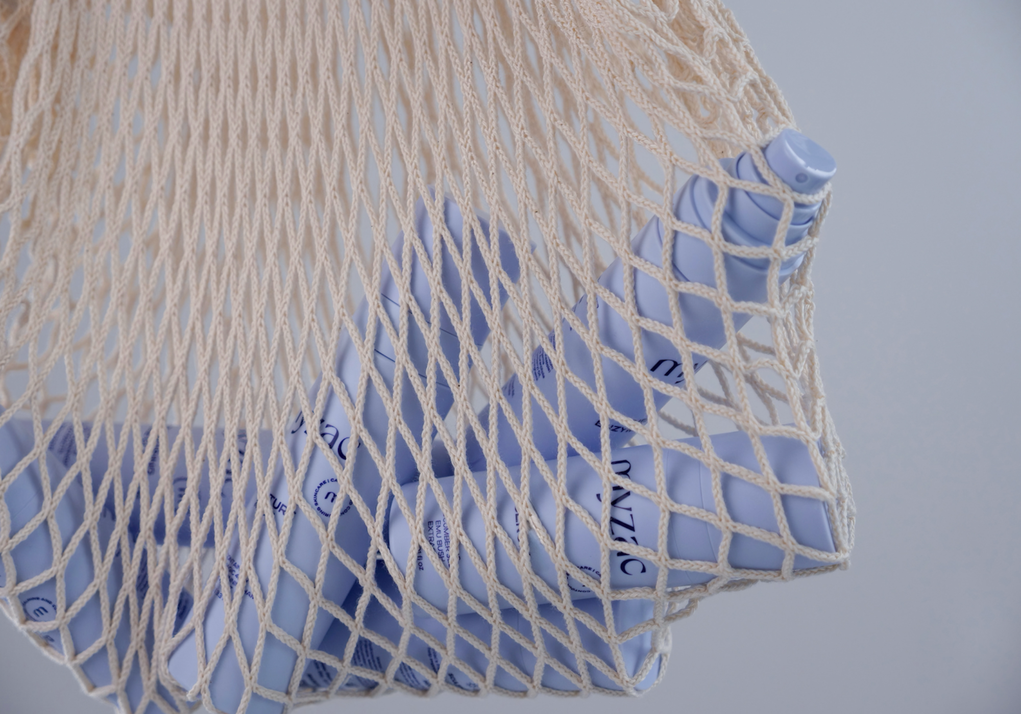MYZAC skincare products displayed in a reusable net bag, highlighting portability and sustainability.