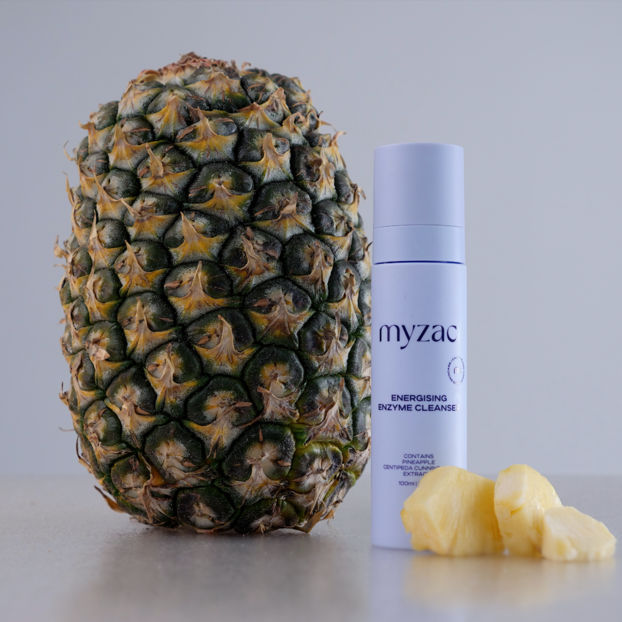 MYZAC Energising Enzyme Cleanser bottle with fresh pineapple, featuring key ingredient highlight.